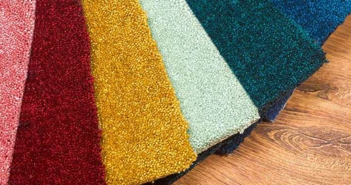 Muestrario de alfombra residencial en varios colores sobre piso de madera